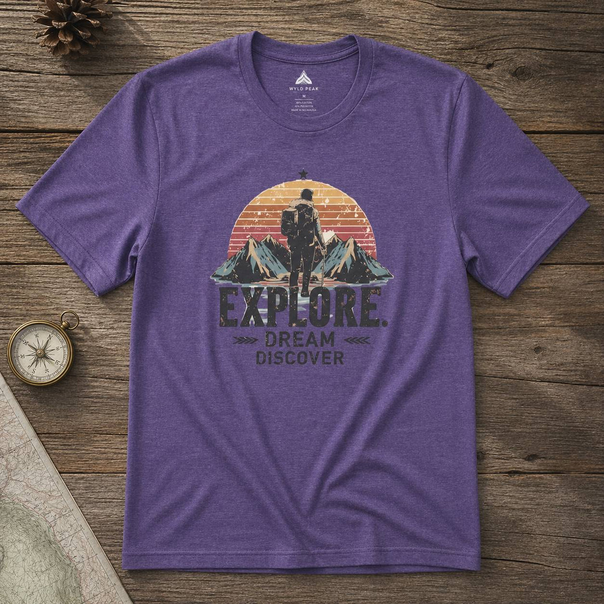 Purple t-shirt with outdoor-themed design on a wooden surface