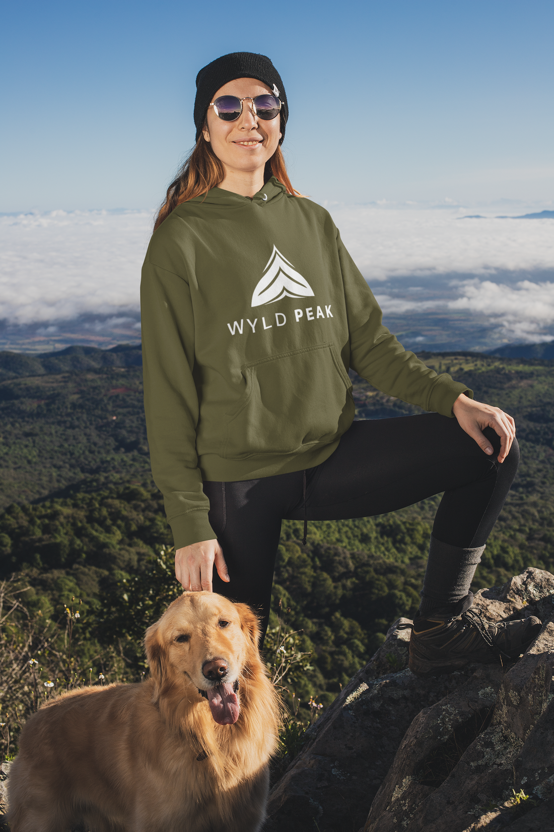 Woman and her dog enjoying the view from a trail peak, both embracing the outdoors in a Wyld Peak logo organic hoodie