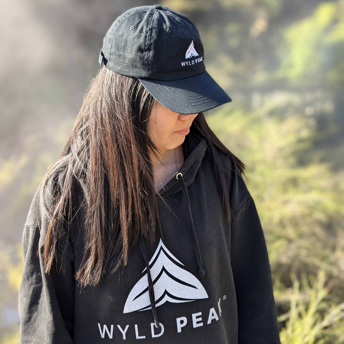 Ann wearing Wyld Peak apparel at Waimangu Volcanic Valley in New Zealand, surrounded by geothermal steam and lush terrain