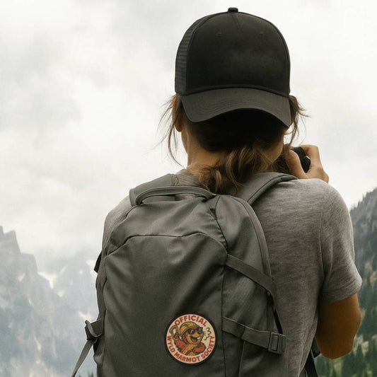 Woman hiking on a trail with a backpack featuring Wyld Peak Marmot Society patch