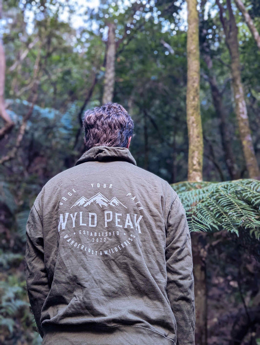 Alexander wearing a Wyld Peak organic hoodie in a lush Pacific Northwest forest, captured from behind
