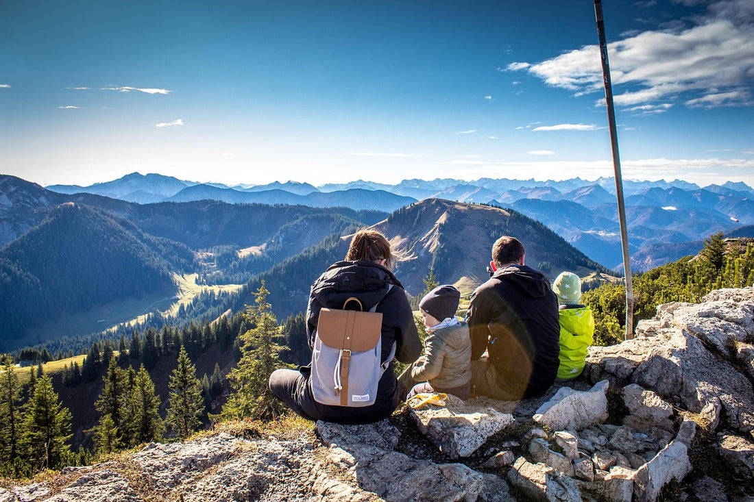 Family celebrating at the top of a hiking trail with panoramic mountain views in the background