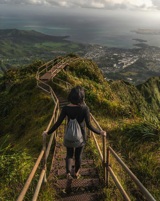 Female hiker descending a lush stair-step trail in Hawaii—tropical trekking adventure