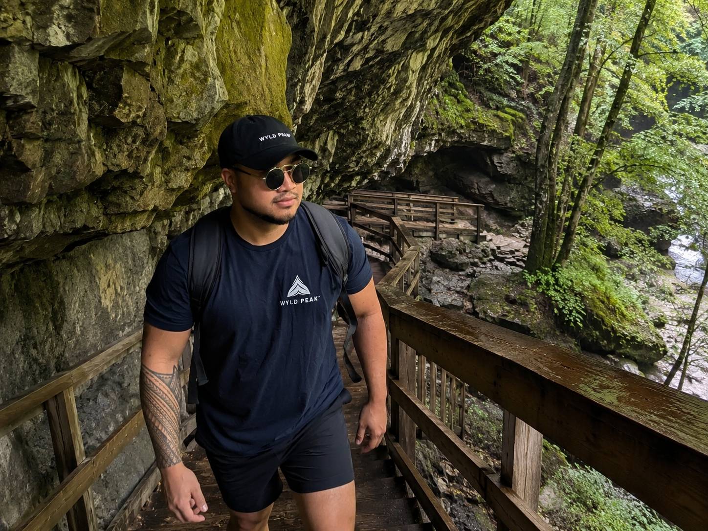 Man hiking in a natural cave with wooden walkway and rocky walls