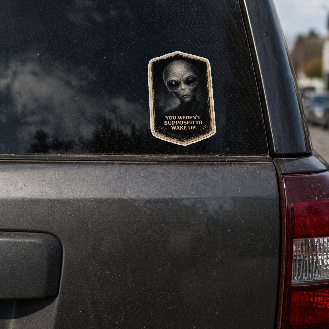 Alien-themed sticker on a car window with text 'YOU WEREN'T SUPPOSED TO WAKE UP'.