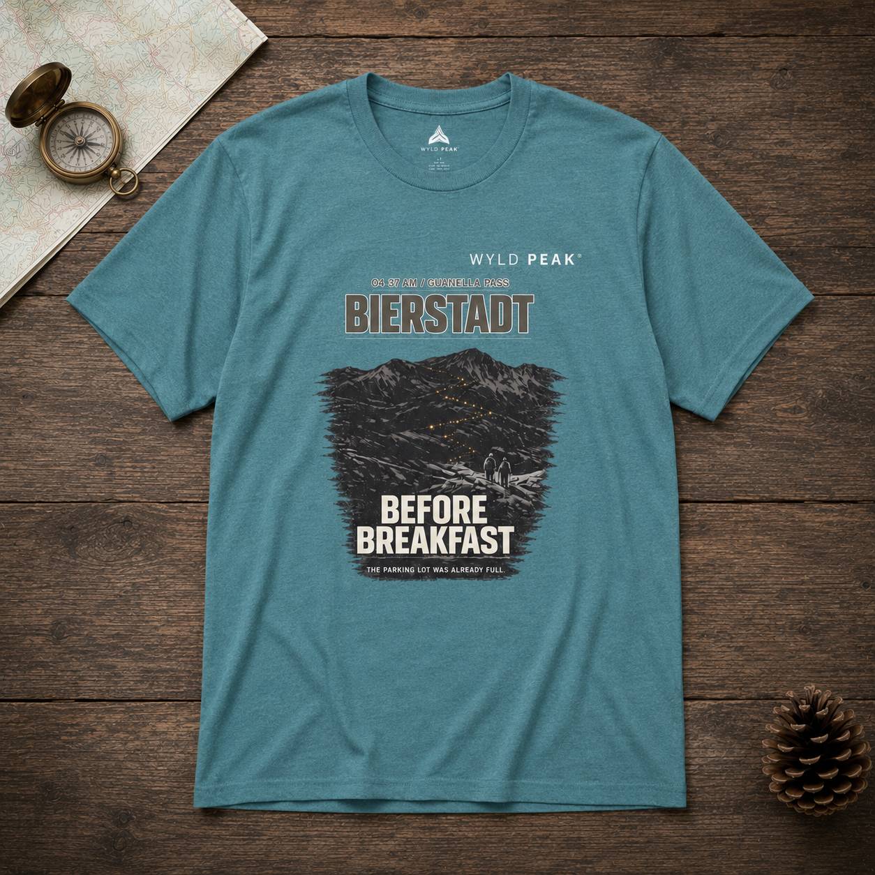 Blue t-shirt with mountain graphic and text on a wooden surface