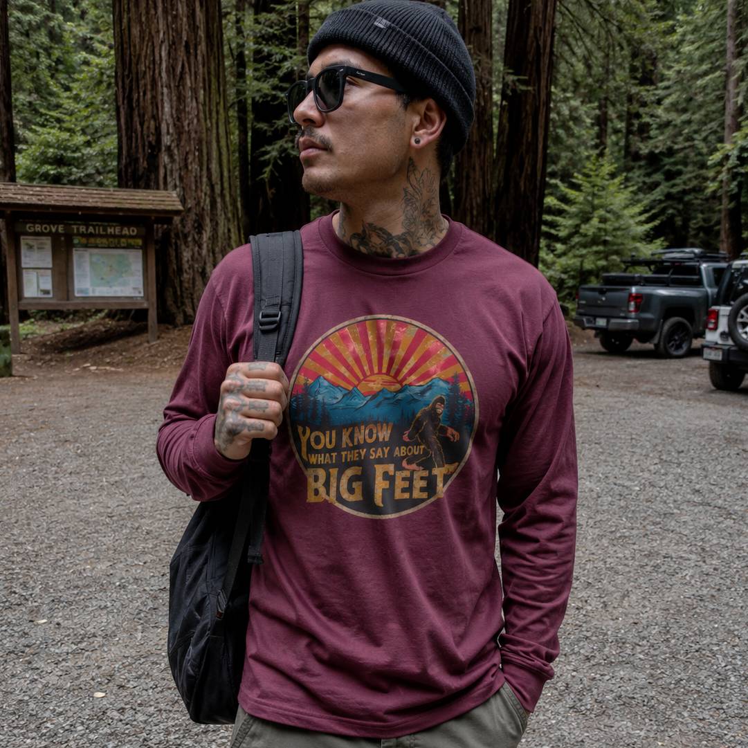 Man wearing a maroon t-shirt with a graphic design in a forest setting