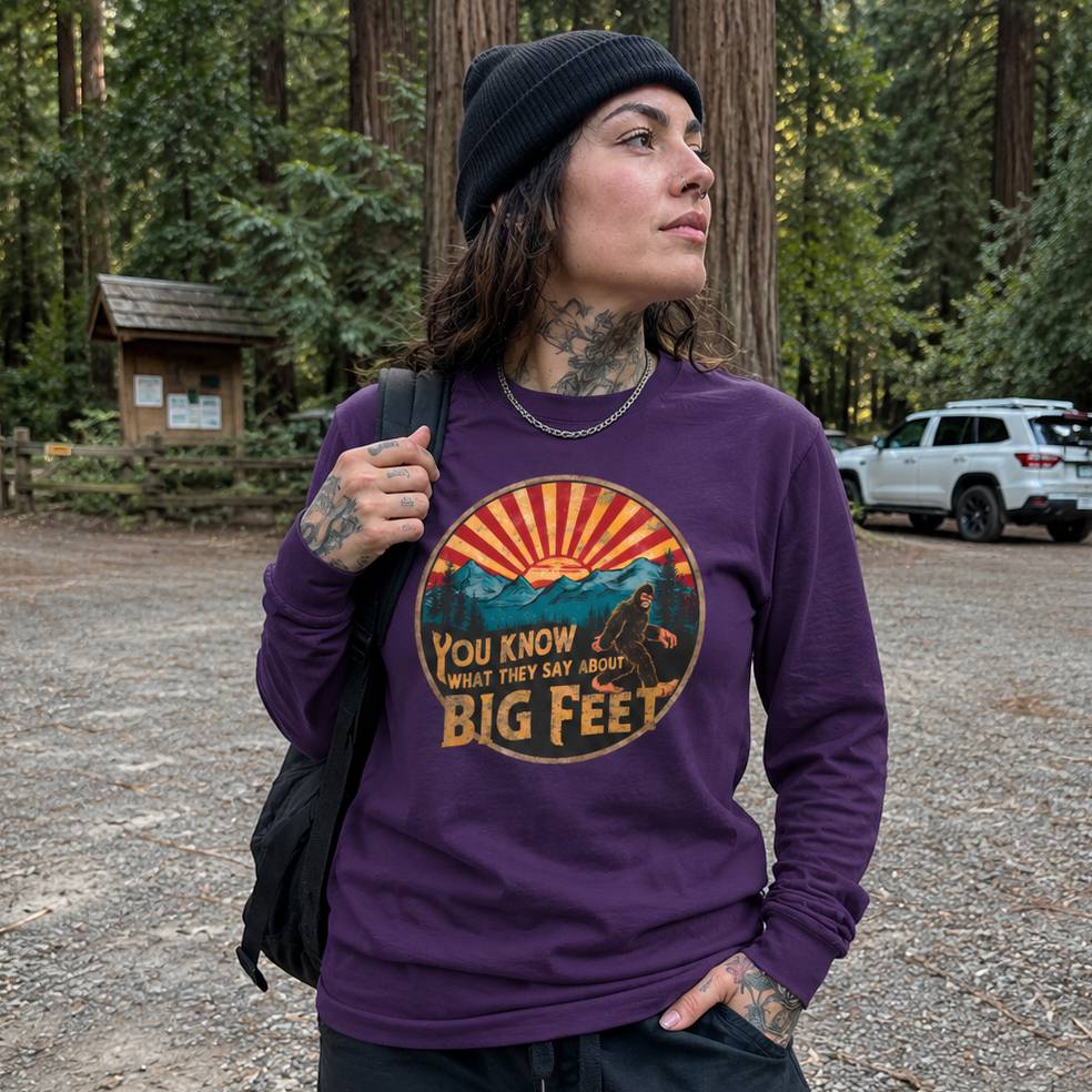 Person wearing a purple sweatshirt with a graphic design and text in a forest setting
