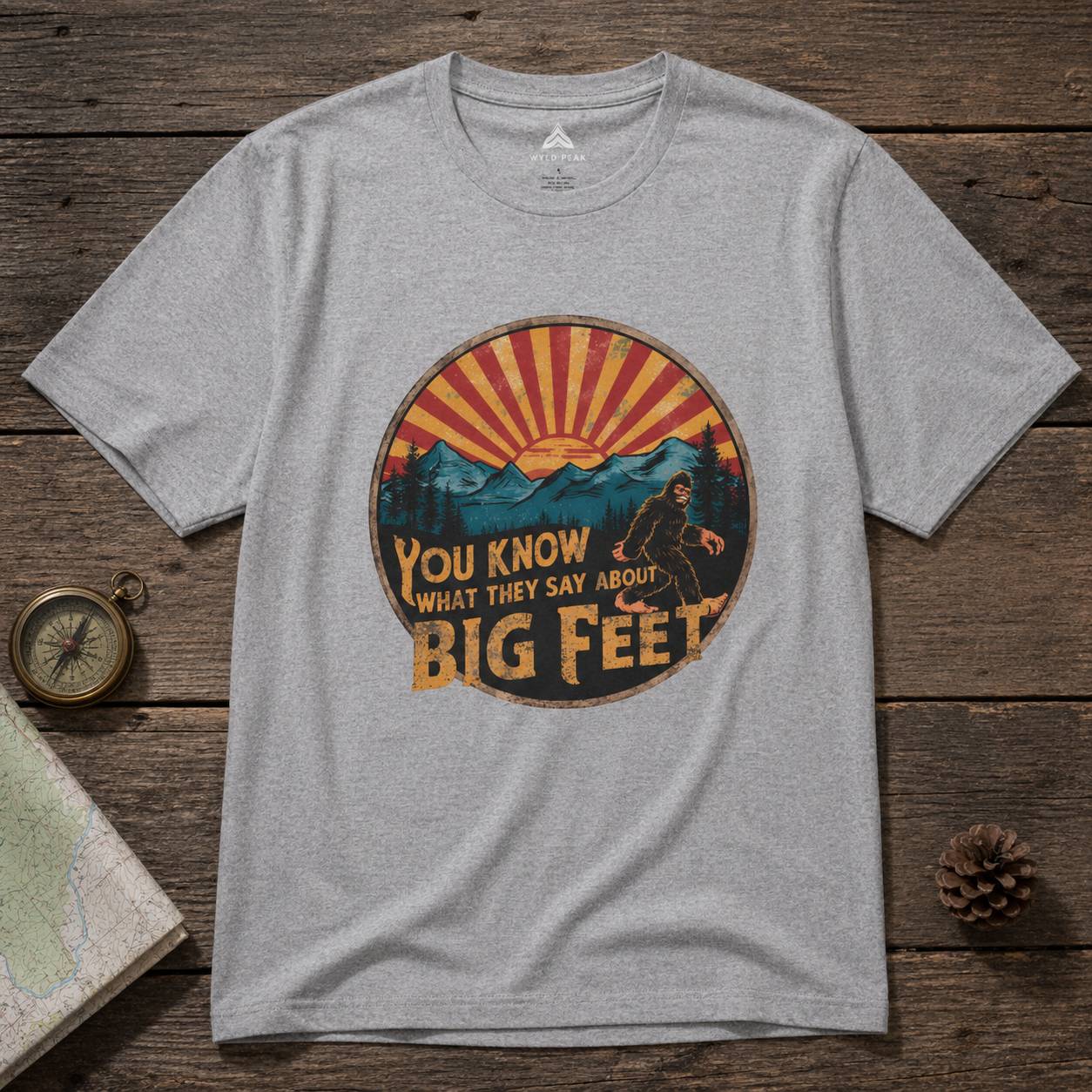 Gray t-shirt with a bigfoot graphic design on a wooden surface