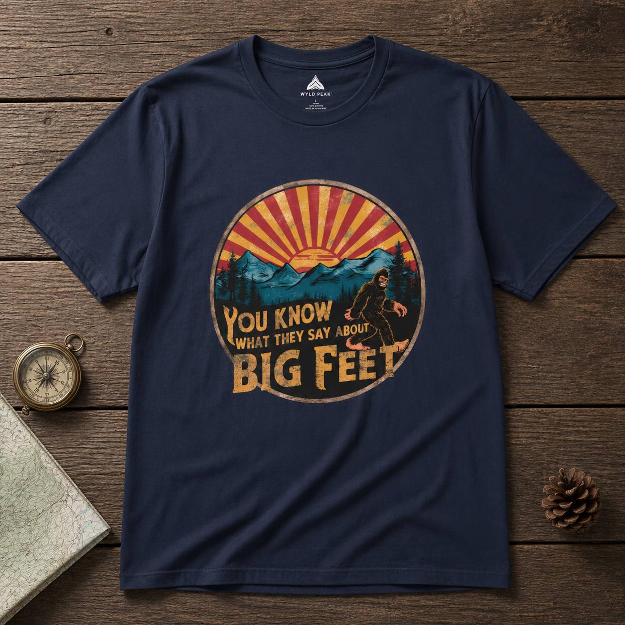 Navy blue t-shirt with a bigfoot graphic design on a wooden surface