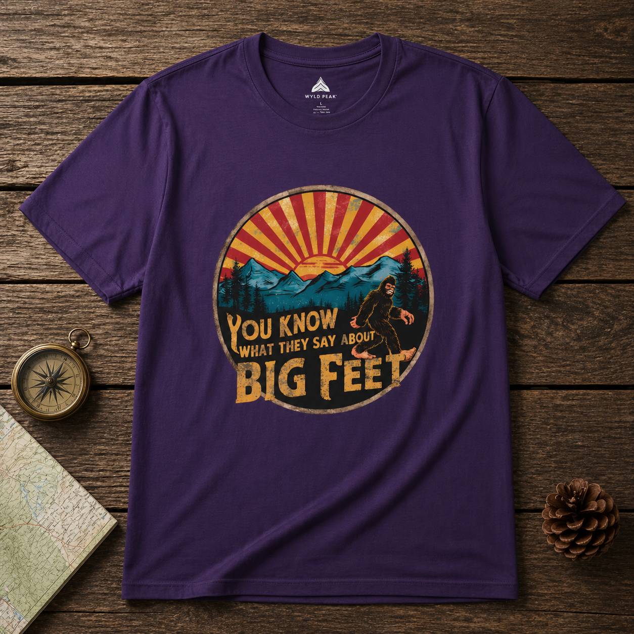 Purple t-shirt with a bigfoot graphic design on a wooden surface