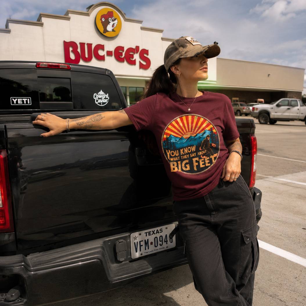 Person leaning against a black truck with a Buc-ee's store in the background