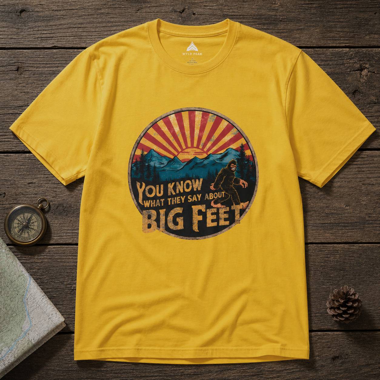 Yellow t-shirt with a bigfoot graphic design on a wooden surface