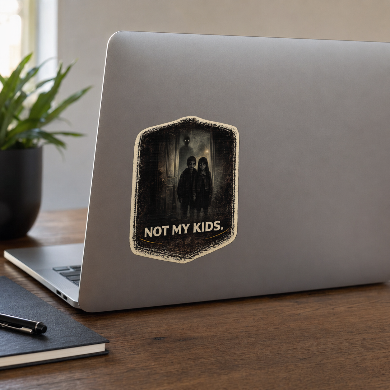 Laptop with a 'Not My Kids' sticker on a wooden desk