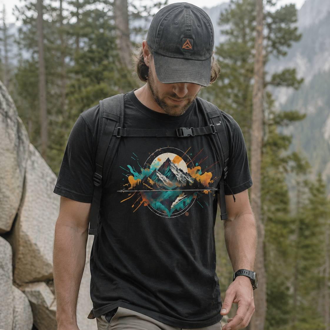 Man wearing a black t-shirt with a mountain design in a forest setting
