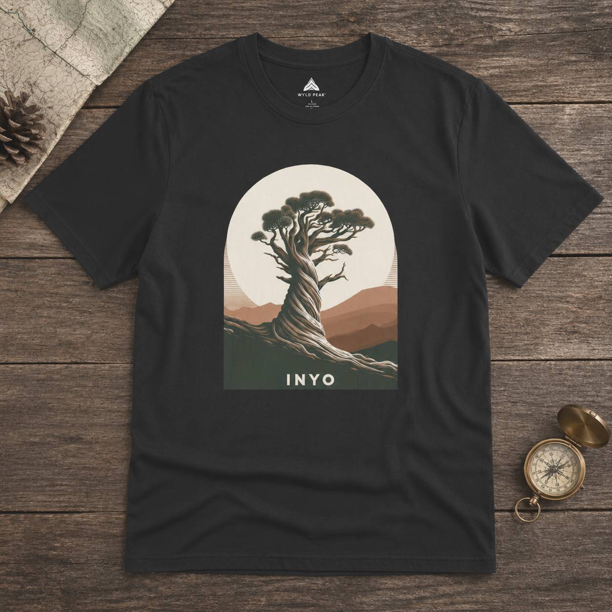 Black t-shirt with a tree graphic and 'INYO' text on a wooden surface
