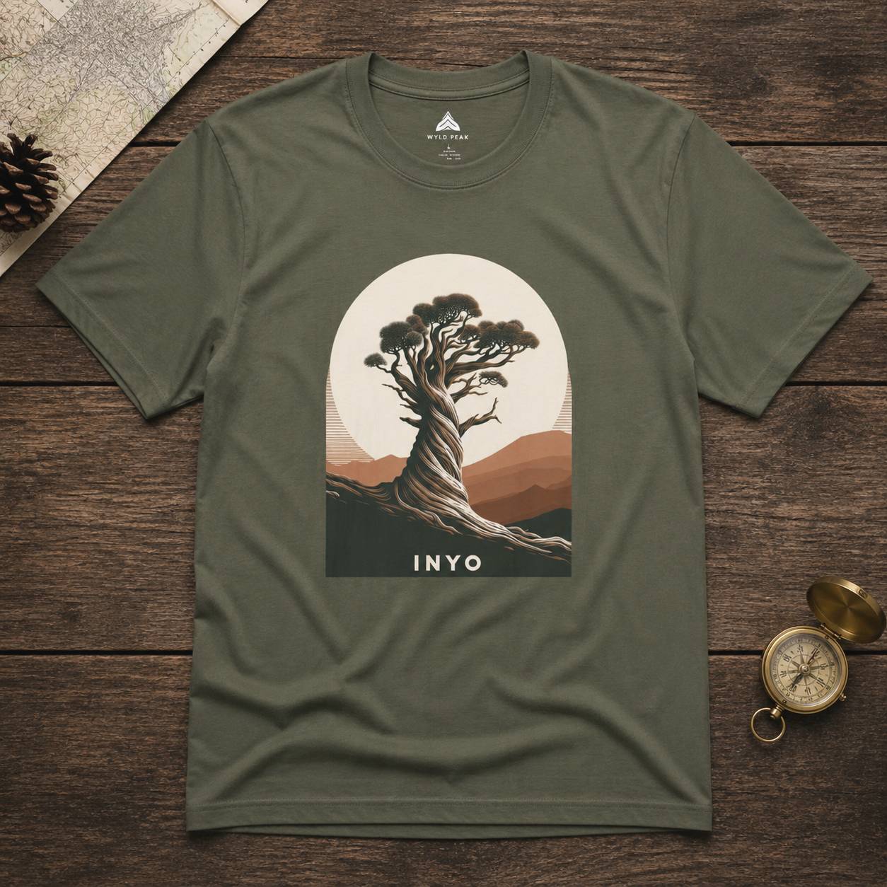 Green t-shirt with a tree graphic and 'INYO' text on a wooden surface.