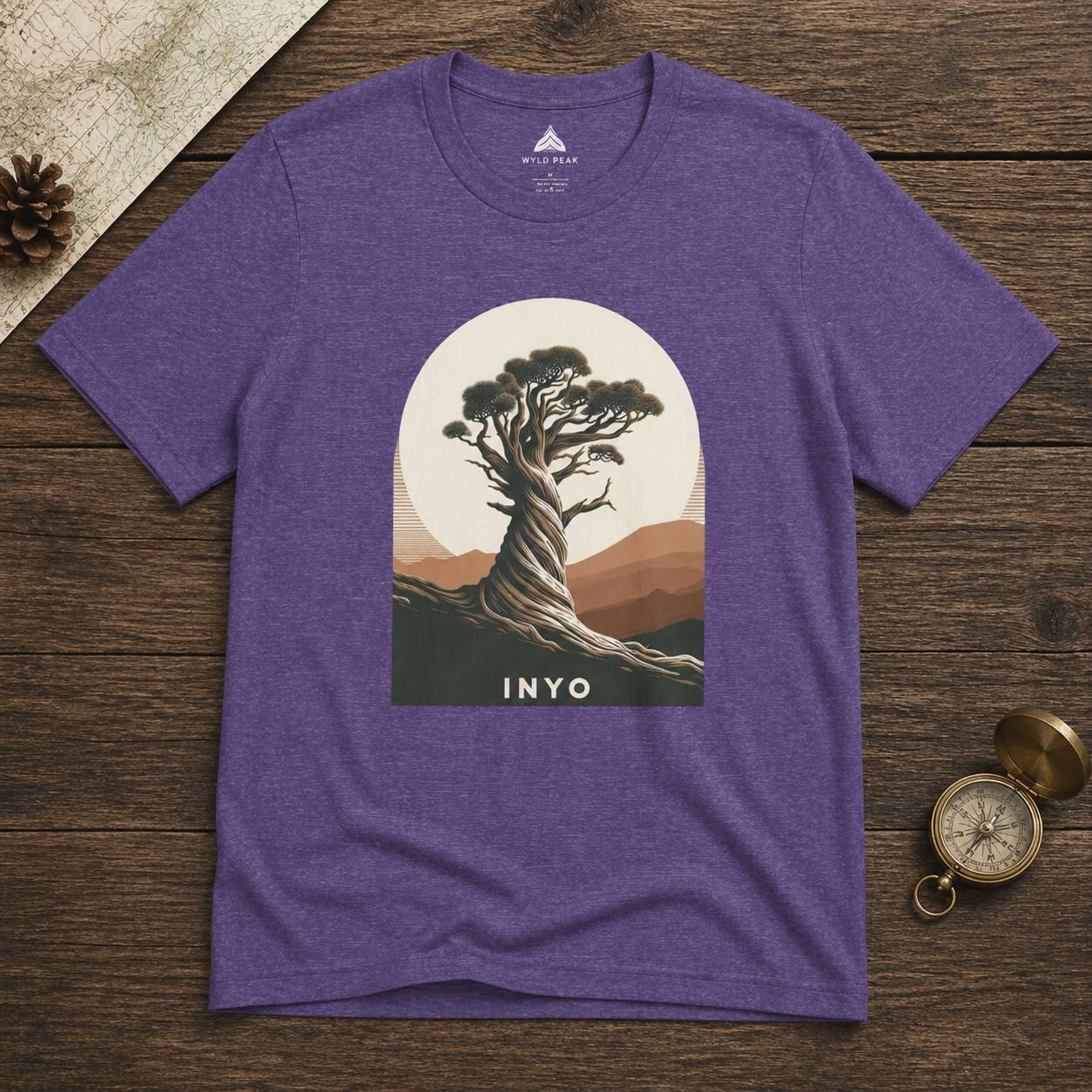 Purple t-shirt with a tree graphic and 'INYO' text on a wooden surface