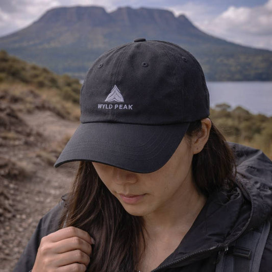 Person wearing a black cap with 'Wyld Peak' logo in a mountainous landscape