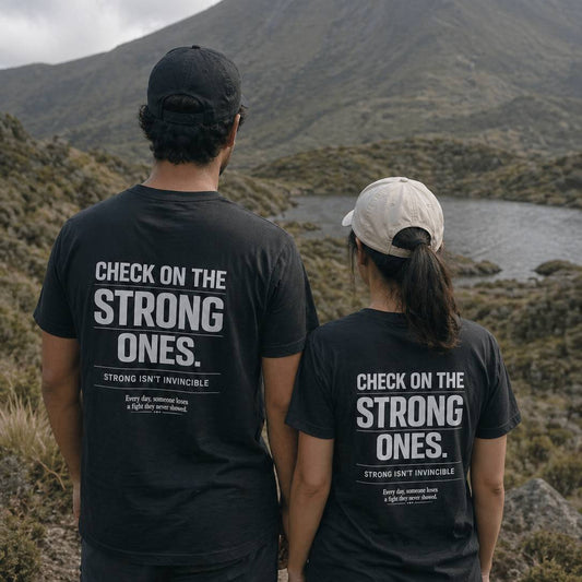 Two people wearing black t-shirts with a motivational message in a mountainous landscape.
