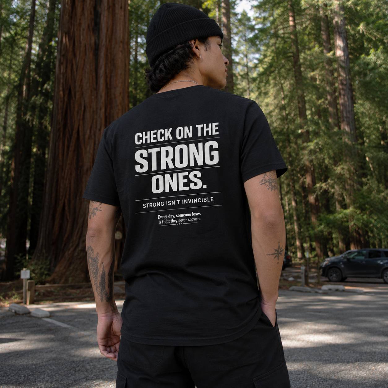 Person wearing a black t-shirt with text in a forest setting
