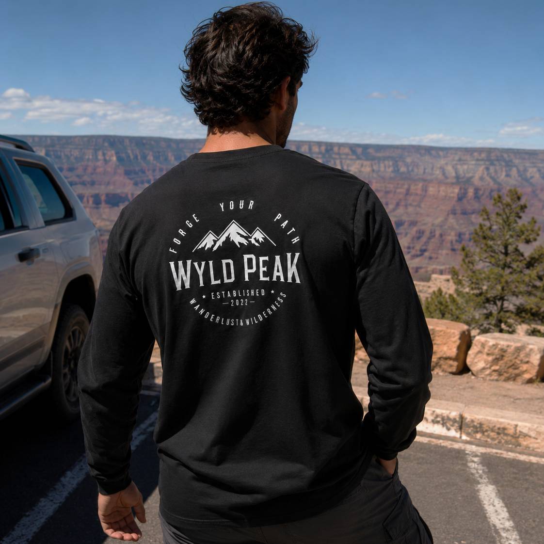 Person wearing a black long-sleeve shirt with 'Wyld Peak' logo at the Grand Canyon.