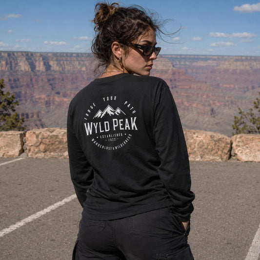 Person wearing a black long-sleeve shirt with 'Wyld Peak' logo at the Grand Canyon.