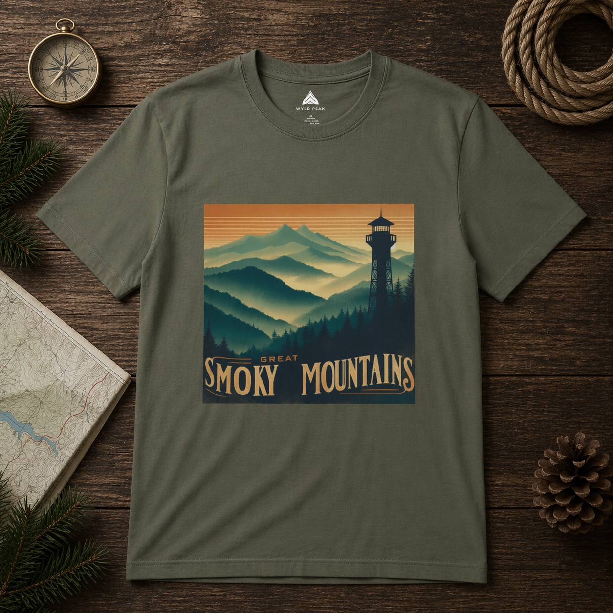 Green t-shirt with 'Great Smoky Mountains' design on a wooden surface with nature-themed items.