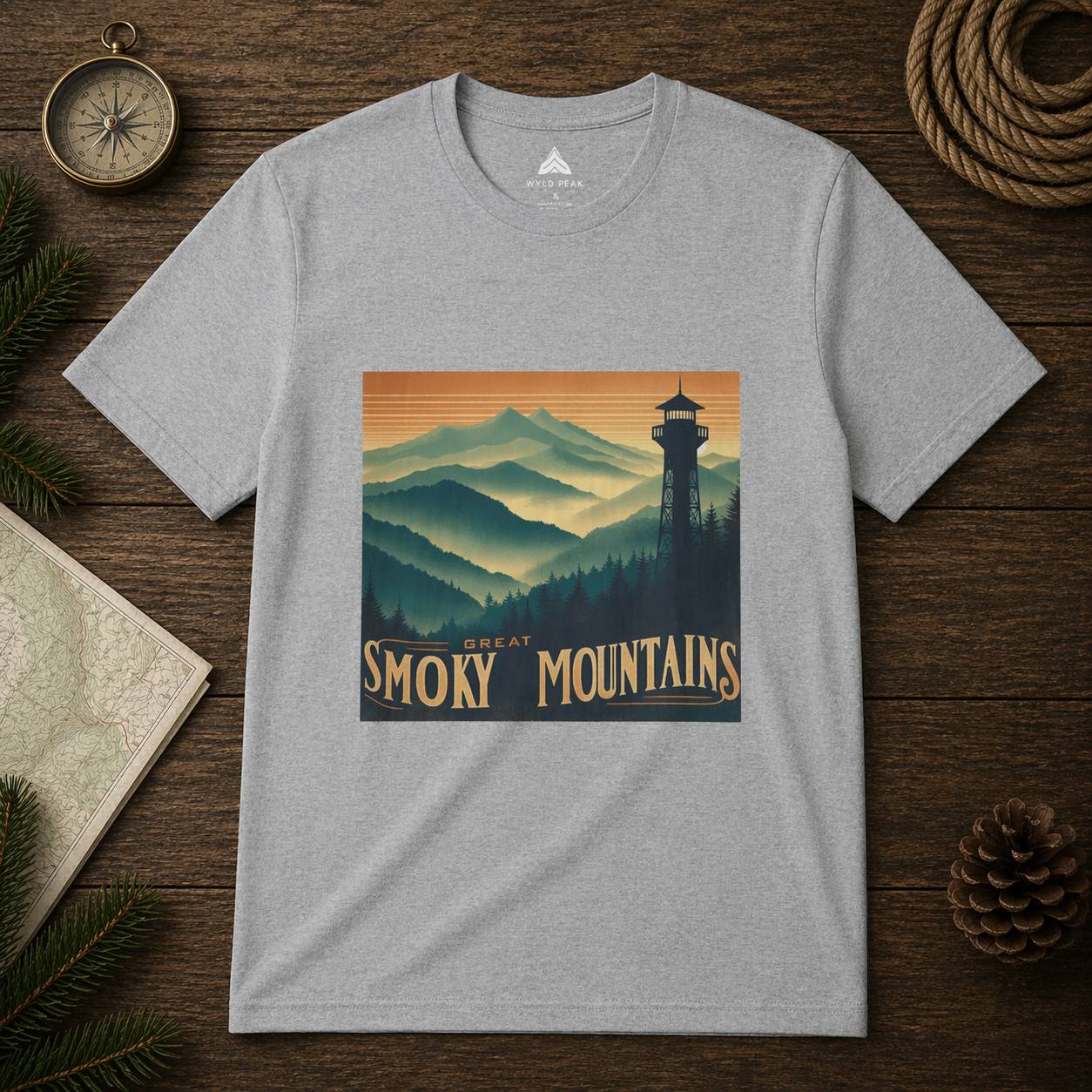 Gray t-shirt with Great Smoky Mountains design on a wooden surface with nature-themed items.