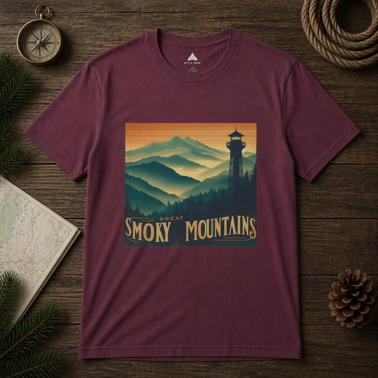 Maroon t-shirt with Great Smoky Mountains design on a wooden surface with nature-themed decor.