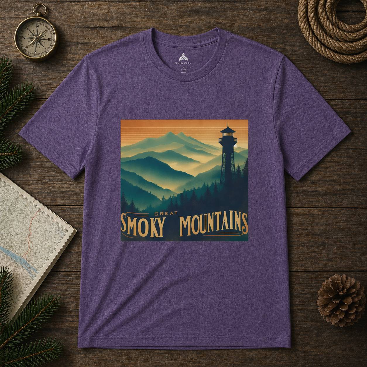 Purple t-shirt with Great Smoky Mountains design on a wooden surface with nature-themed items.
