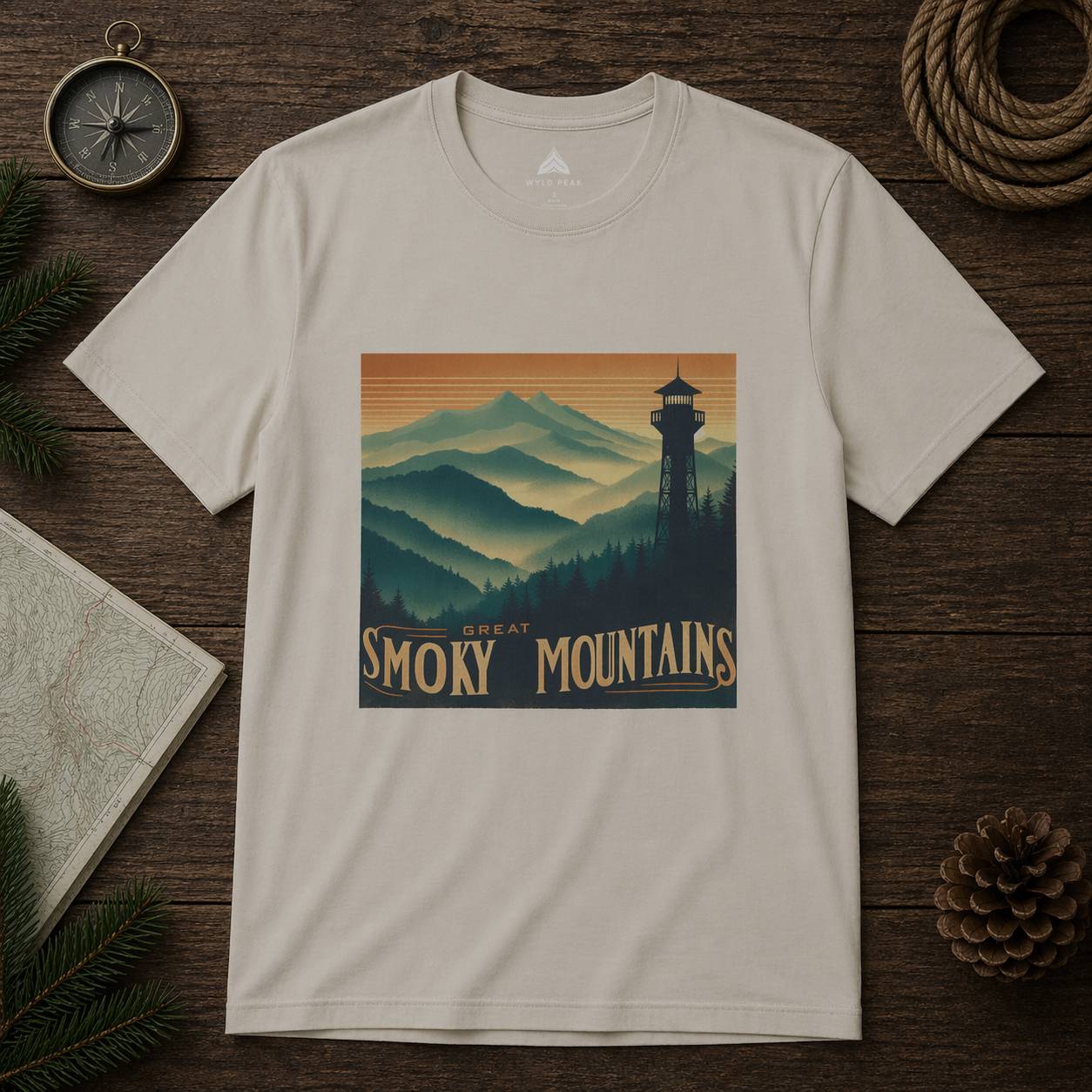 Beige t-shirt with Great Smoky Mountains design on a wooden surface with nature-themed items.