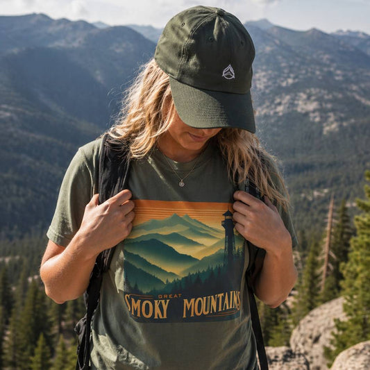 Person wearing a 'Great Smoky Mountains' t-shirt with a scenic design, standing in a mountainous landscape.