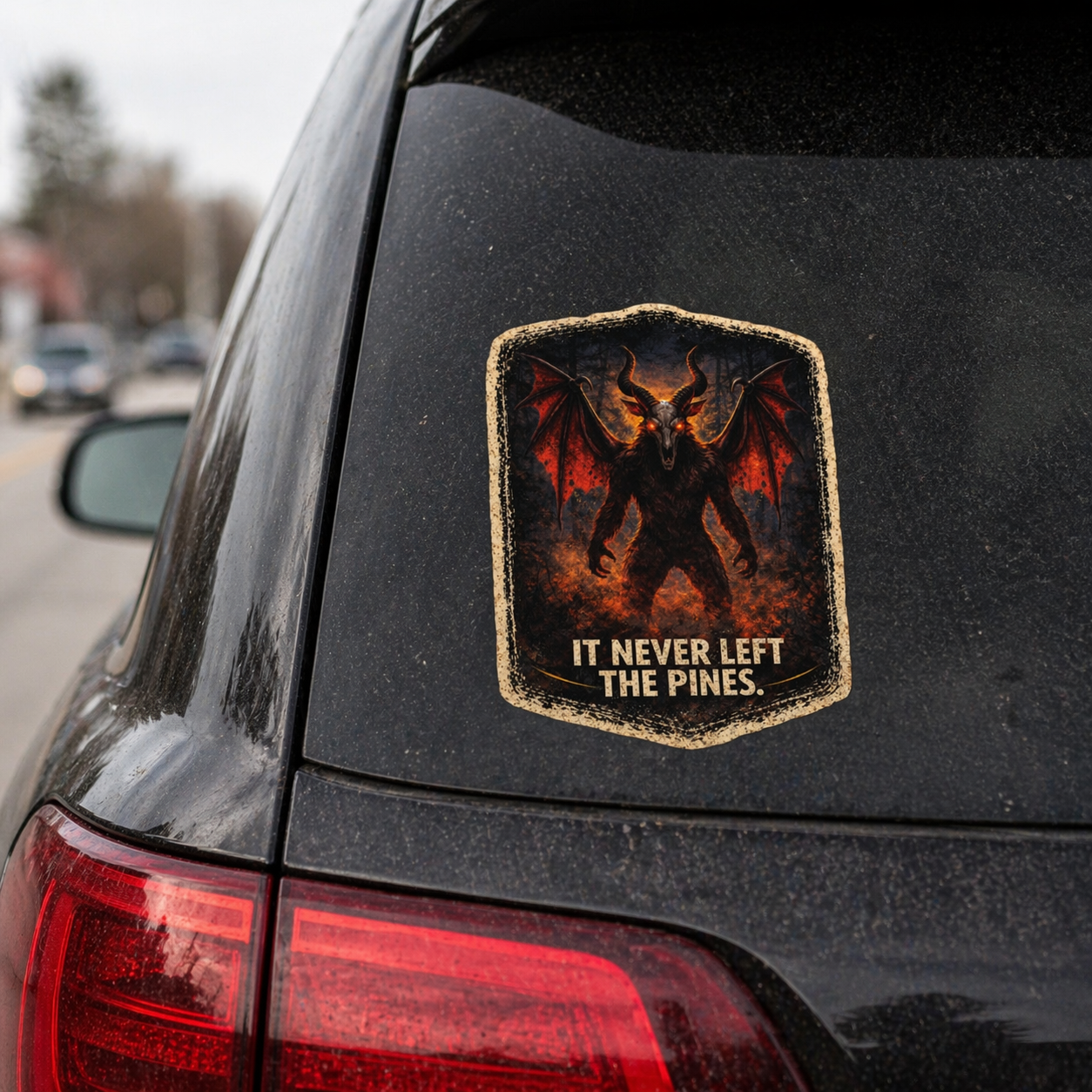 Sticker on a car's rear window with a dragon design and text 'It Never Left The Pines'.