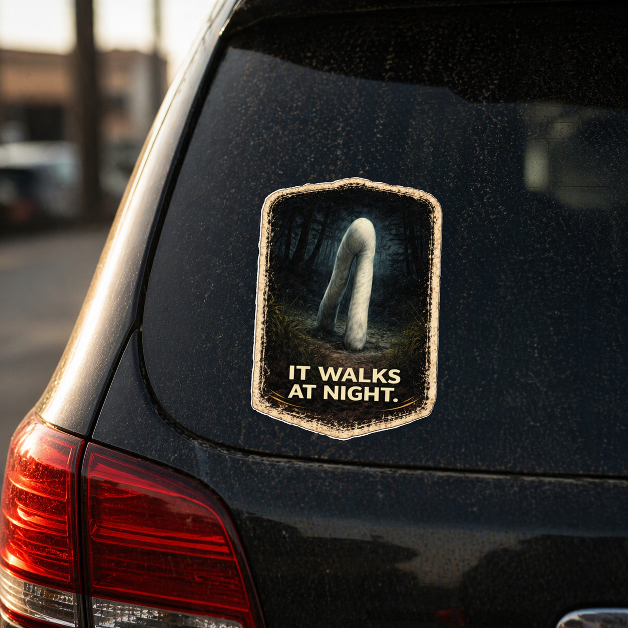 Car sticker with a ghostly figure and text 'It Walks at Night' on a black car.