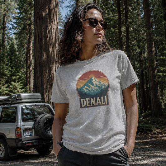 Person wearing a t-shirt with Denali logo in a forest setting