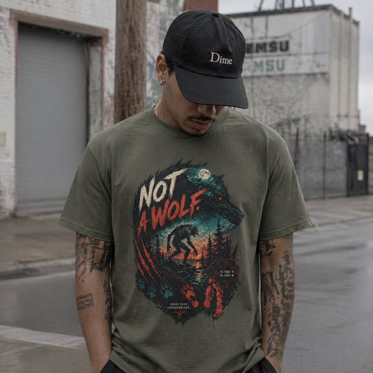 Man wearing a green t-shirt with 'Not a Wolf' graphic and a black cap in an urban setting.