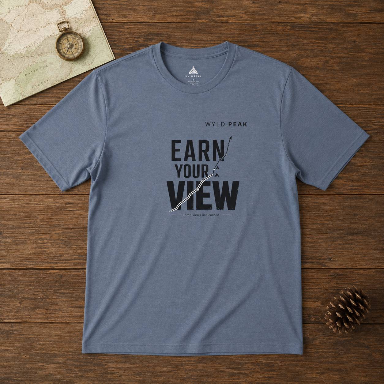 Blue t-shirt with 'Earn Your View' text on a wooden surface