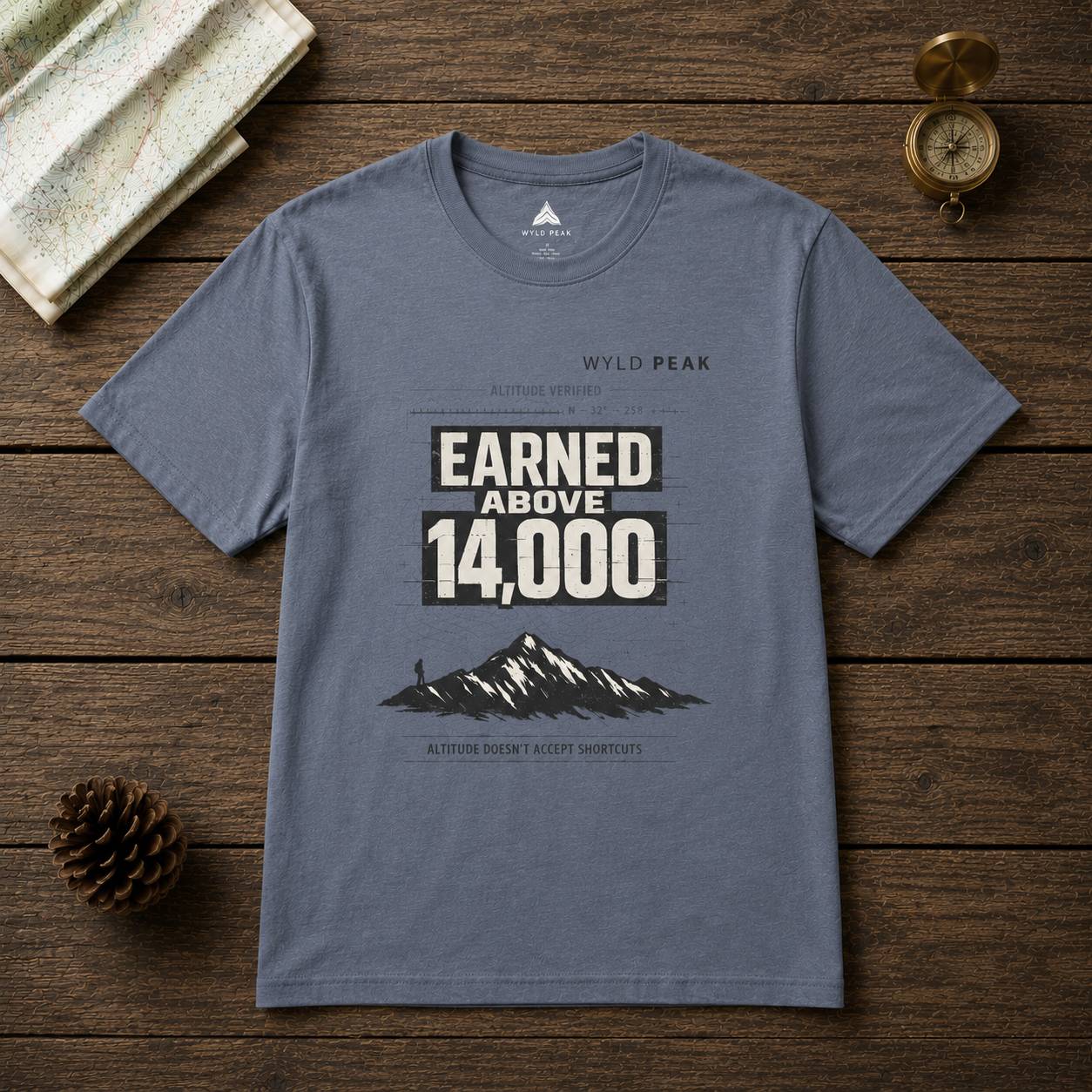 Gray t-shirt with mountain graphic and text on a wooden surface