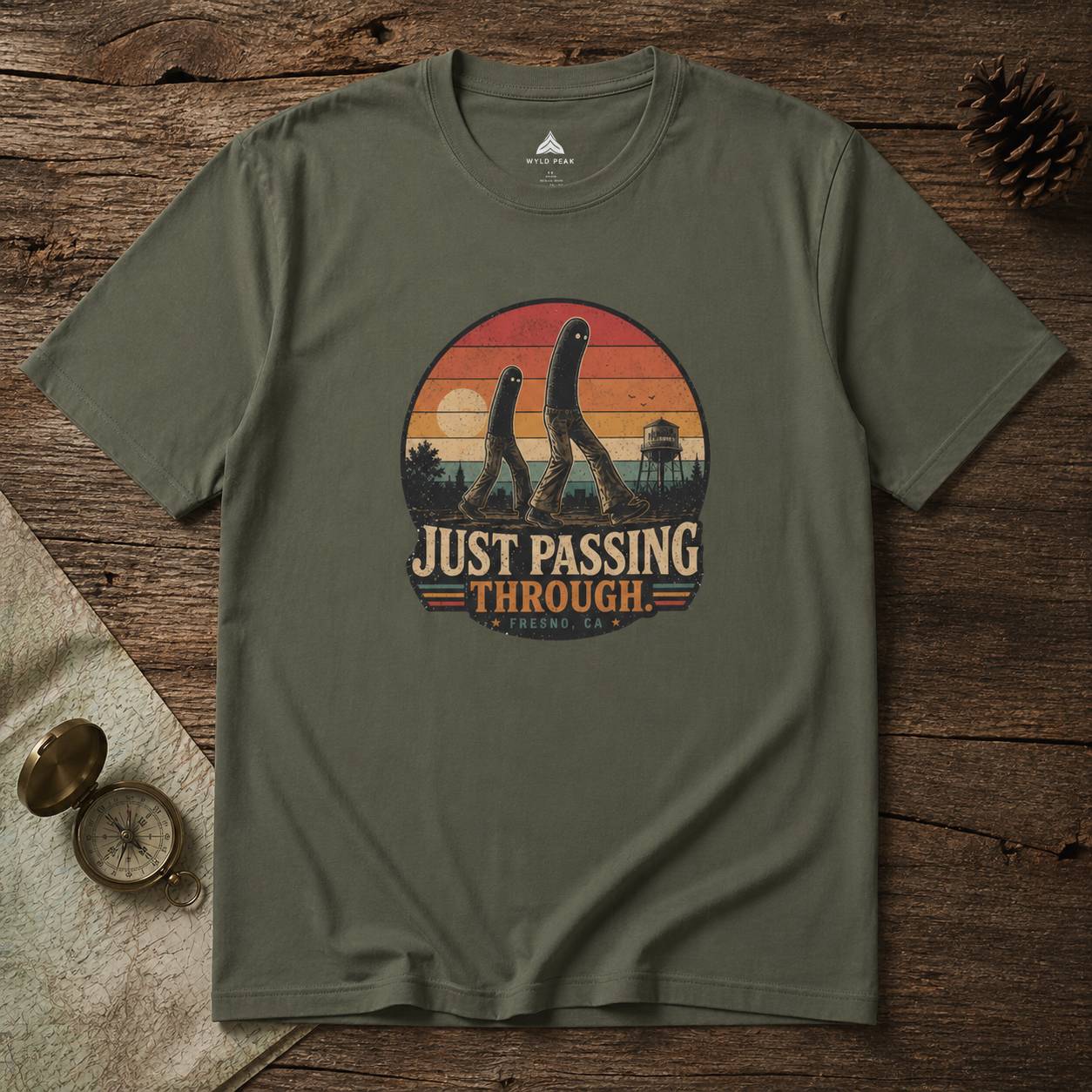 Green t-shirt with 'Just Passing Through' fresno nightcrawler graphic on a wooden surface