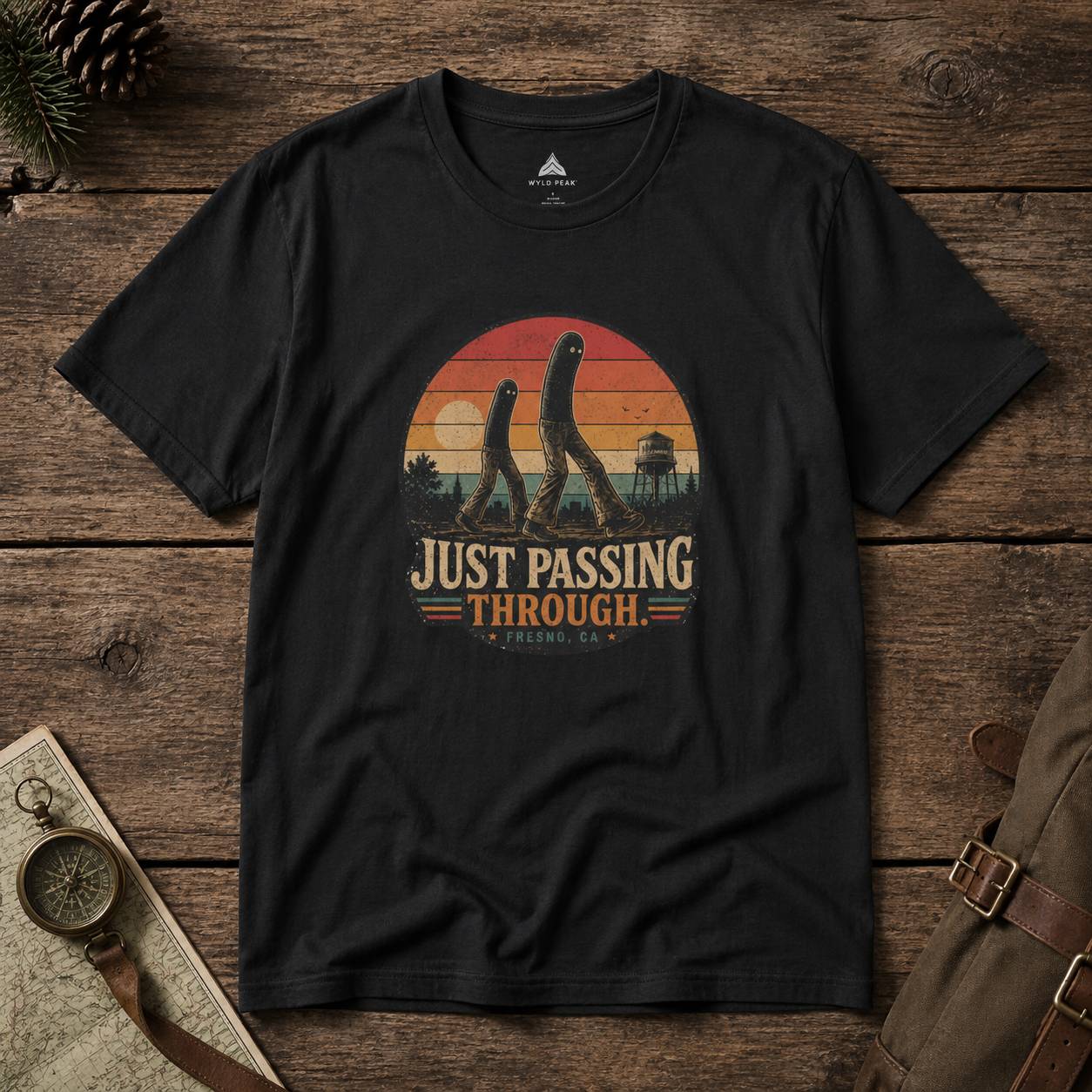 Black t-shirt with 'Just Passing Through' fresno nightcrawler graphic on a wooden surface