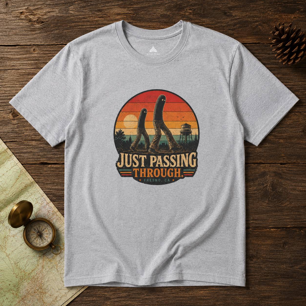 Gray t-shirt with Fresno Nightcrawler 'Just Passing Through' graphic on a wooden surface
