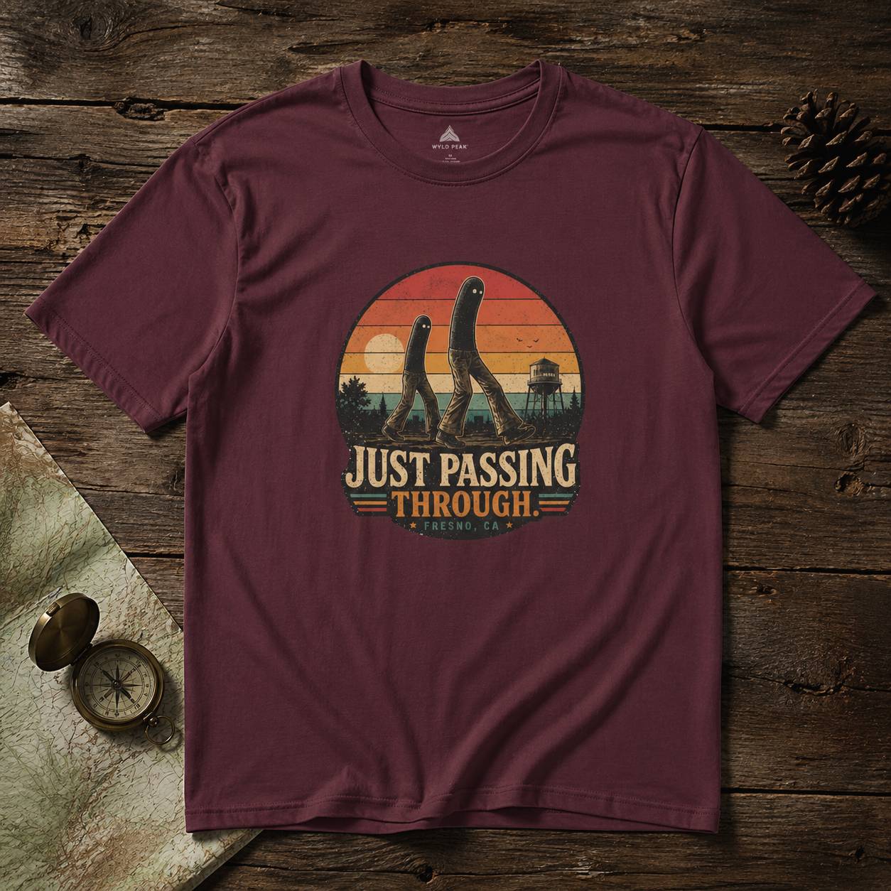 Maroon t-shirt with 'Just Passing Through' fresno nightcrawler graphic on a wooden surface
