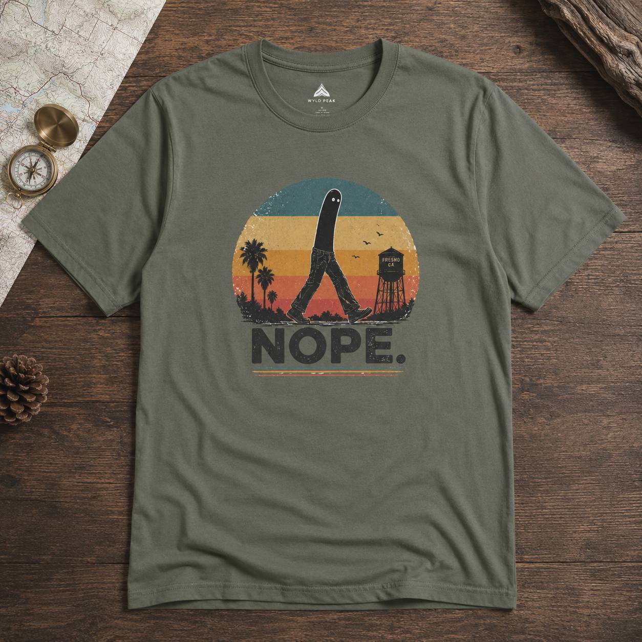 Green t-shirt with 'NOPE.' fresno nightcrawler graphic design on a wooden surface