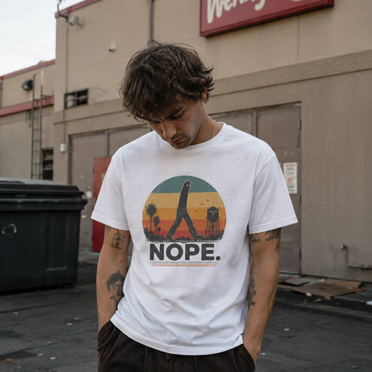 Person wearing a white t-shirt with a graphic design and text, standing in front of a building.