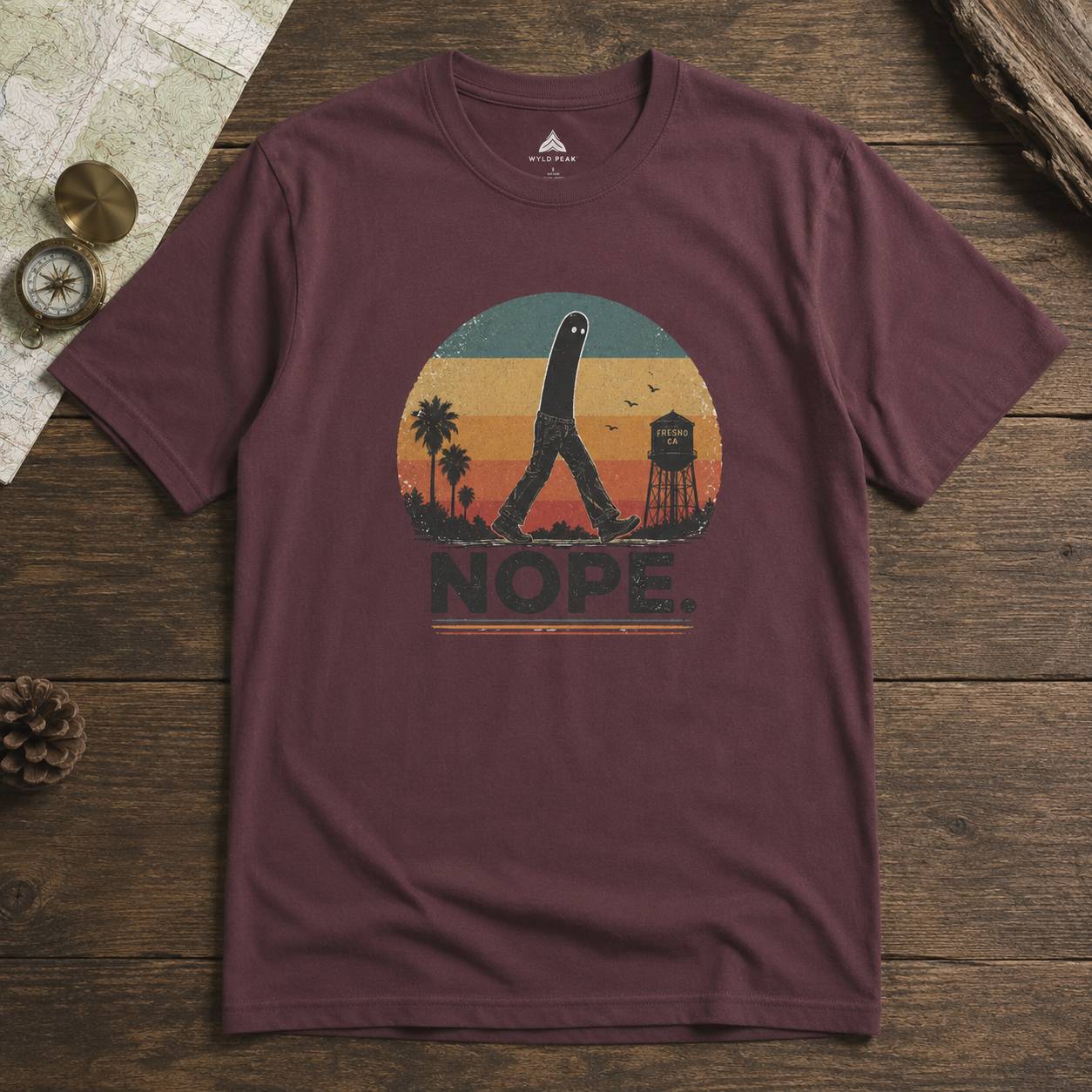 Maroon t-shirt with a fresno nightcrawler graphic design on a wooden surface