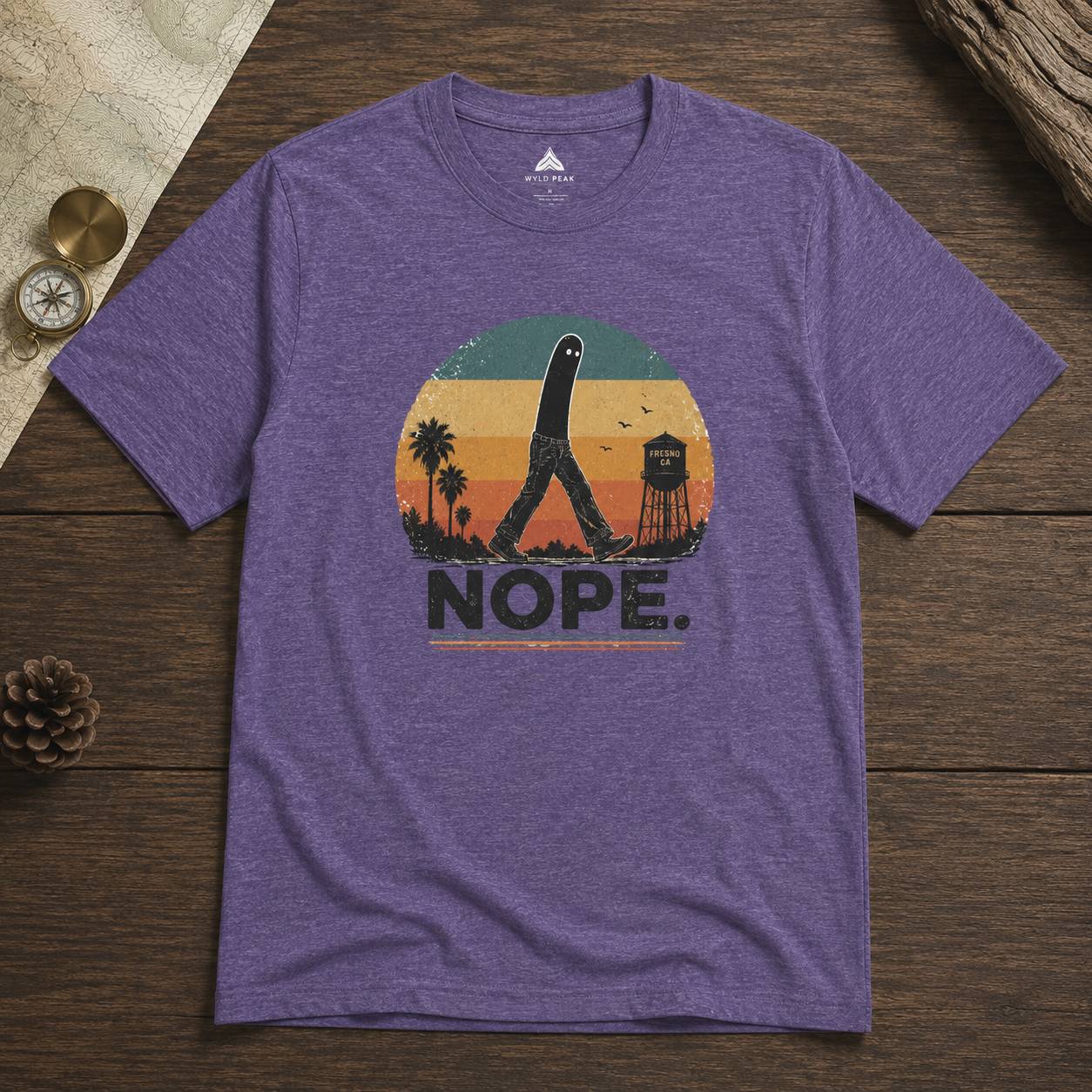 Purple t-shirt with a fresno nightcrawler graphic design and 'NOPE.' text on a wooden surface