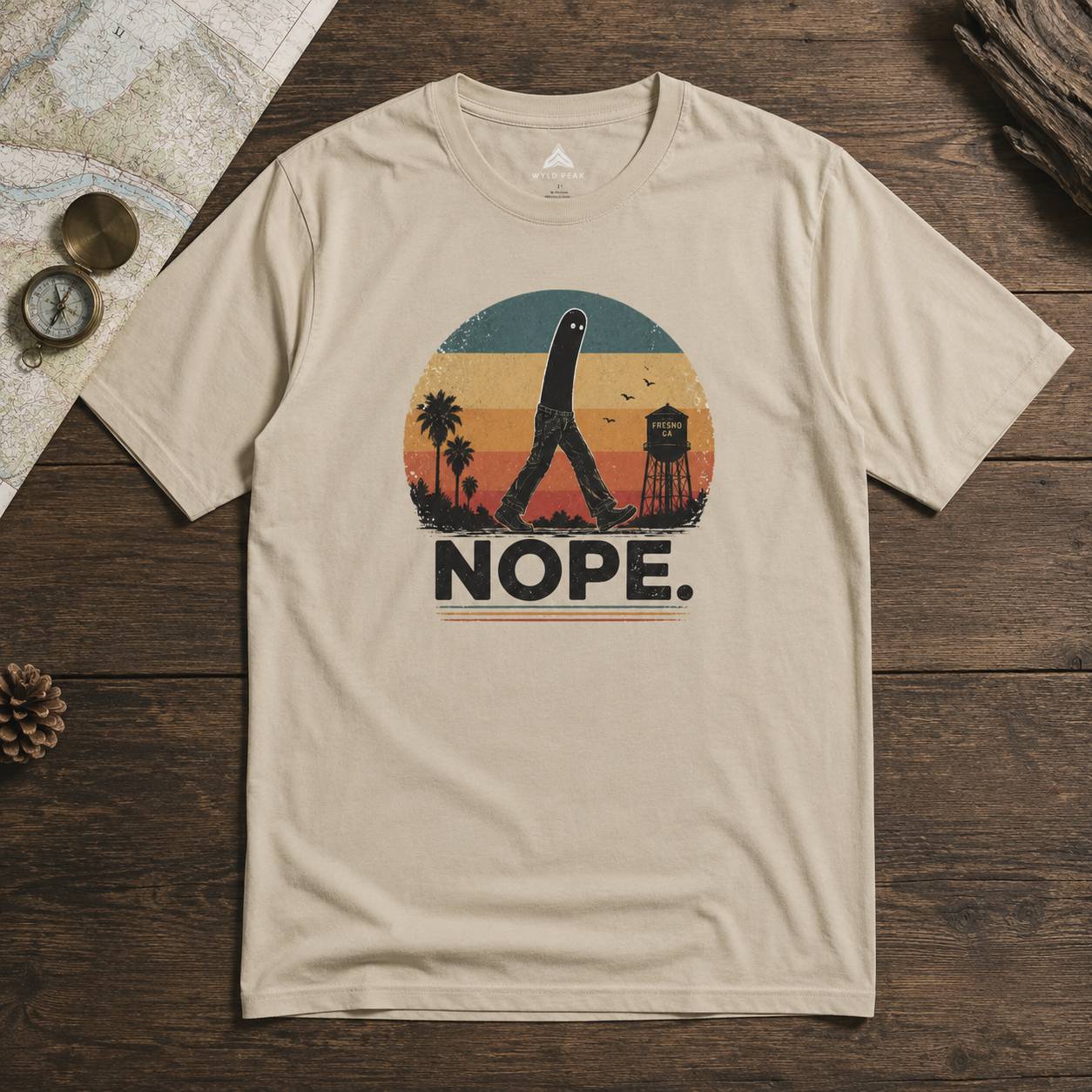 Beige t-shirt with a fresno nightcrawler graphic design and 'NOPE.' text on a wooden surface
