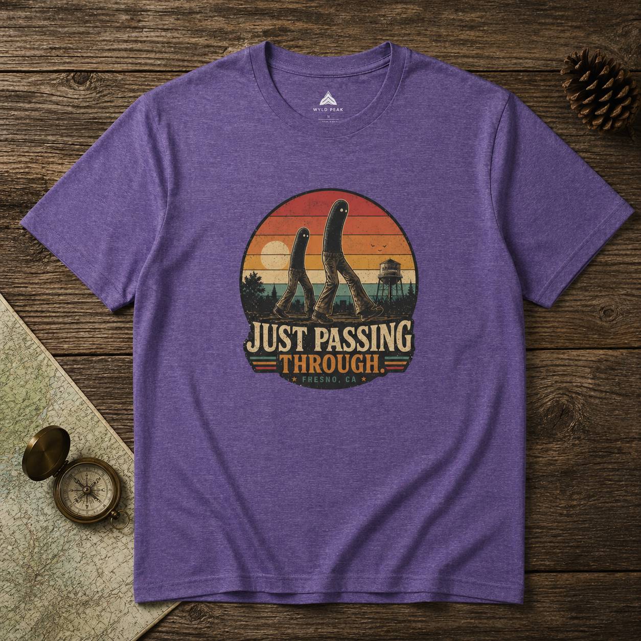 Purple t-shirt with 'Just Passing Through' fresno nightcrawler graphic on a wooden surface
