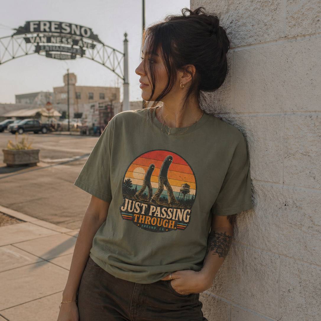 Woman wearing a t-shirt with a fresno nightcrawler graphic design leaning against a wall in an urban setting.